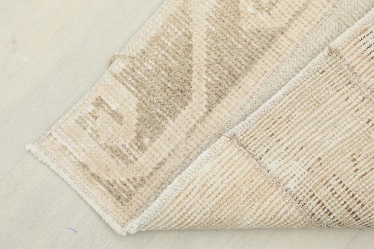 Corner of the rug folded to show the cotton foundation and the reverse side of the hand-knotting.