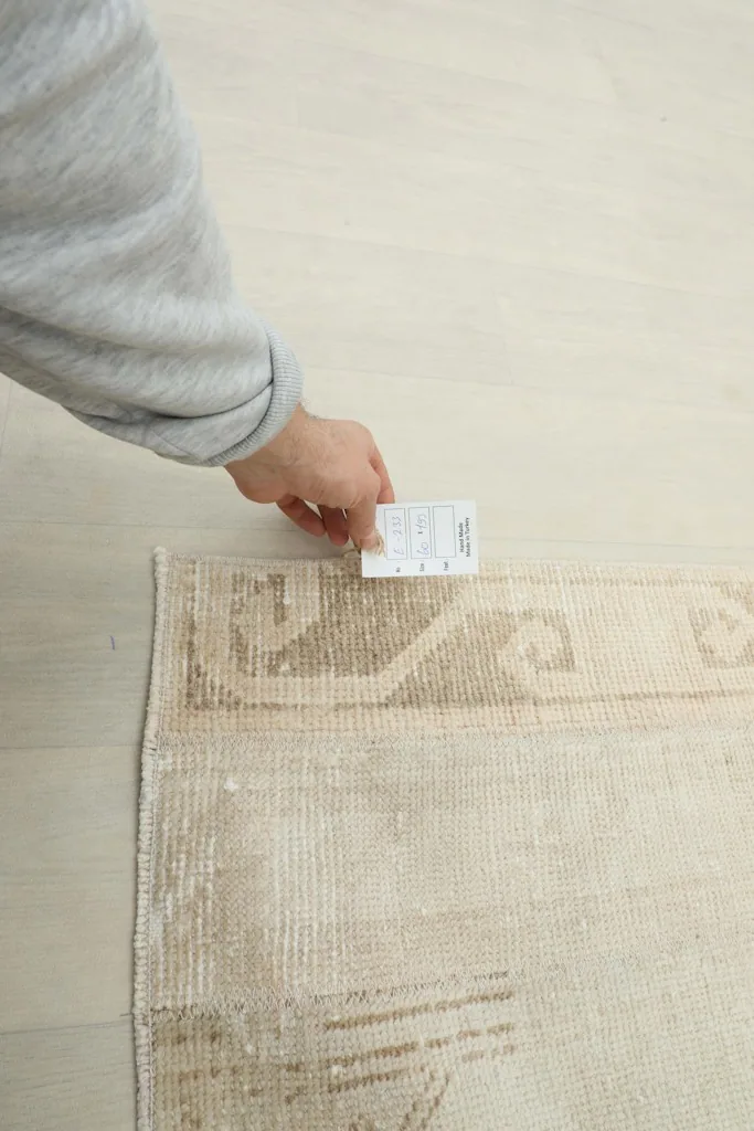 Hand holding a business card next to the rug's border, for scale reference of the pattern.