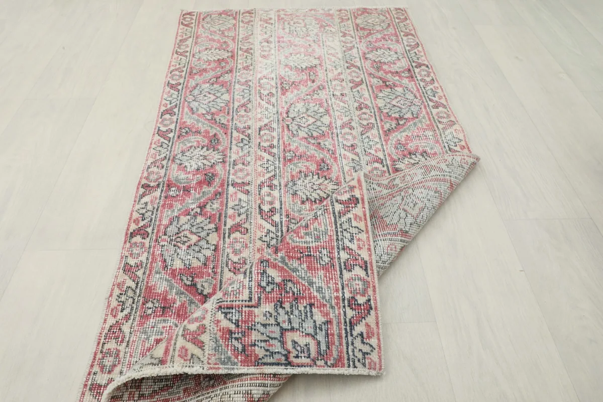 The vintage rug partially rolled, showcasing its flexibility and material.