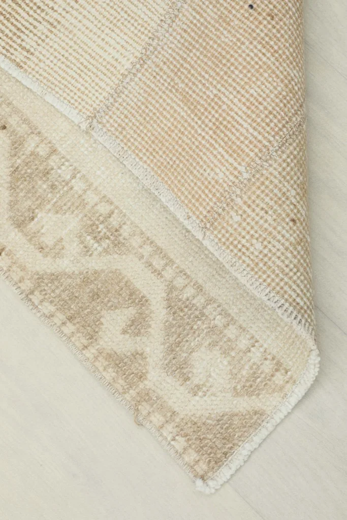 Corner of the rug folded back, revealing the wool pile and cotton foundation