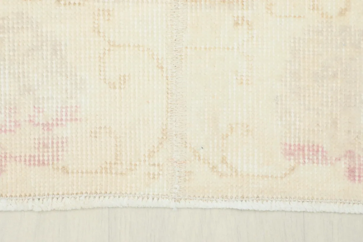 Close-up of the rug's edge, showing the faint rose patterns near the border and the short fringe.
