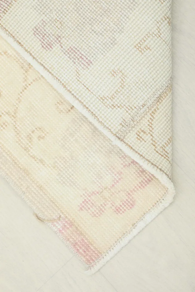 Corner of the rug folded back to reveal the cotton foundation and the reverse side of the knotting.