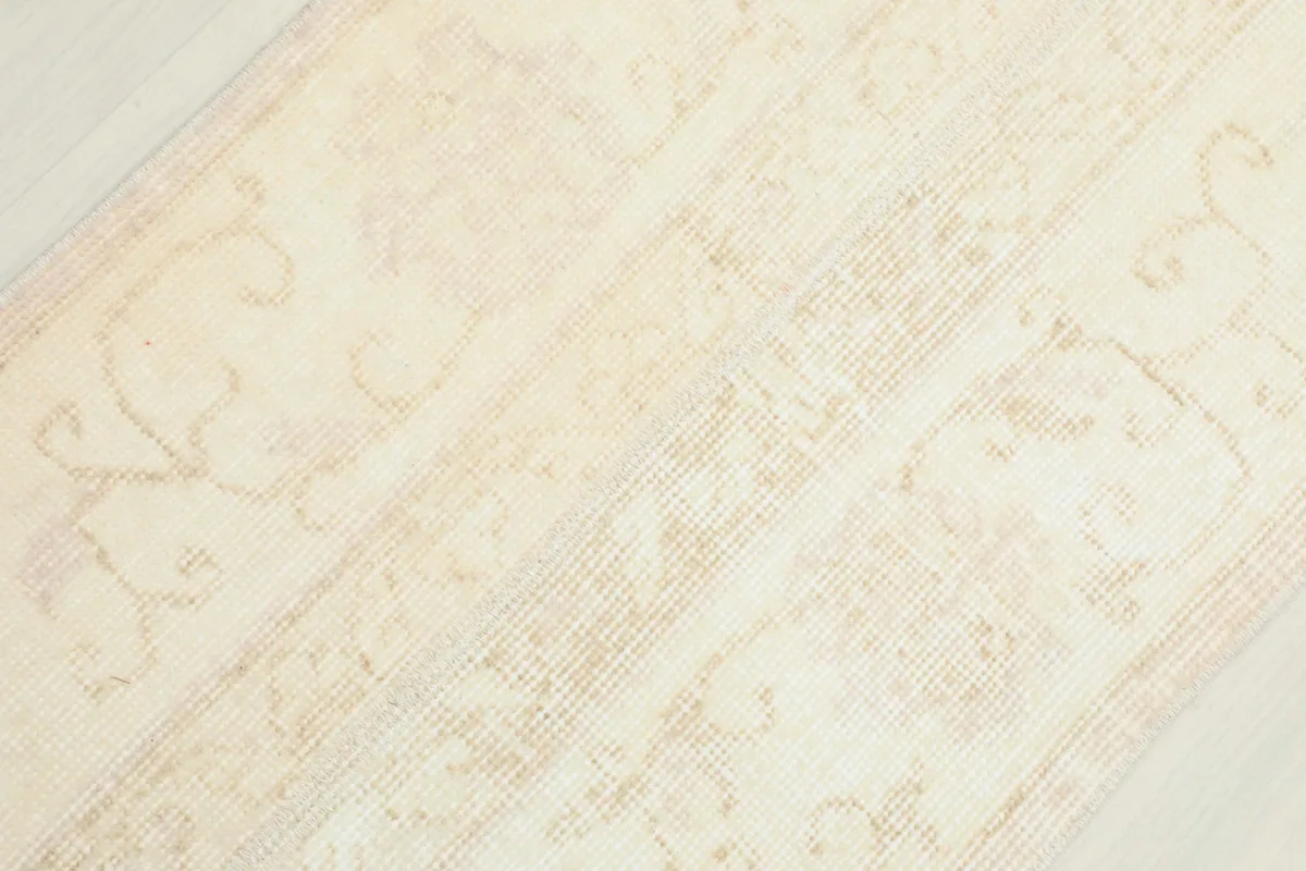 Overhead close-up of the rug's texture and muted cream and tan colors across the surface.