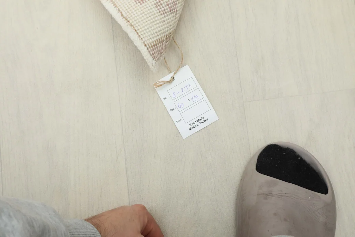 Size tag for the 1'7" x 3'11" rug next to a foot for scale, showing origin from Turkey.