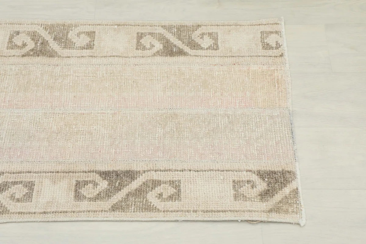 Close-up of the rug's beige field and brown tribal border pattern