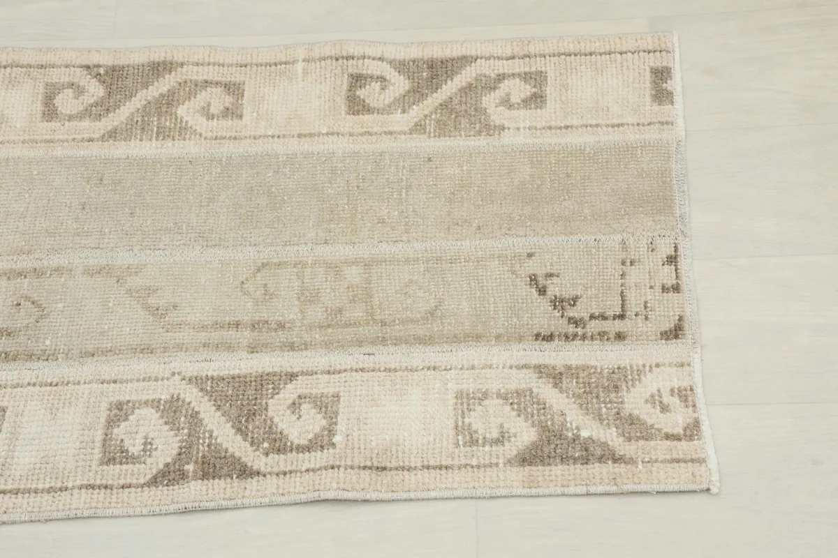 Close-up view of the end of the beige runner, highlighting the brown geometric border pattern.