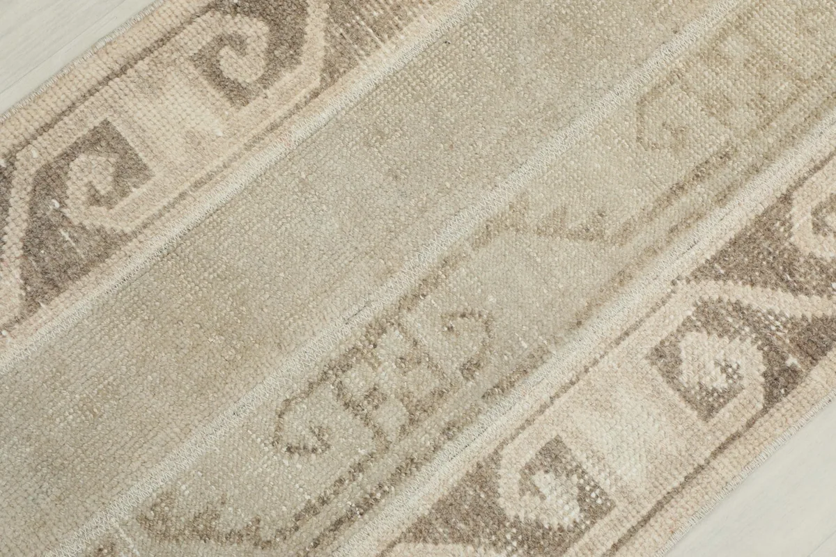 Close-up angled shot of the beige and brown runner, focusing on the central patchwork-like field.