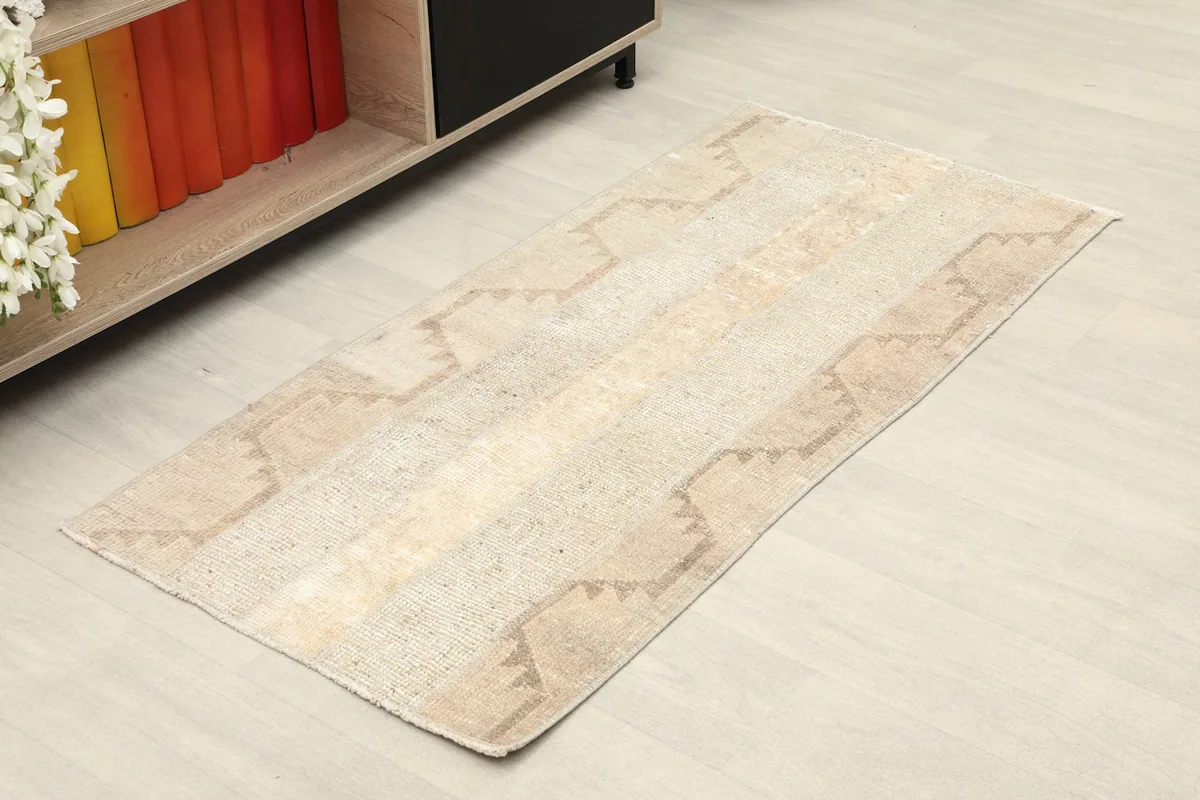 Angled view of the beige and tan vintage rug, showing its full design and dimensions.