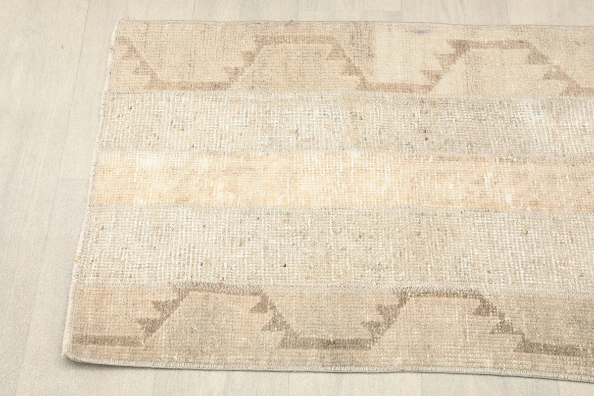Close-up view of the rug's beige and tan striped pattern with tribal geometric motifs.
