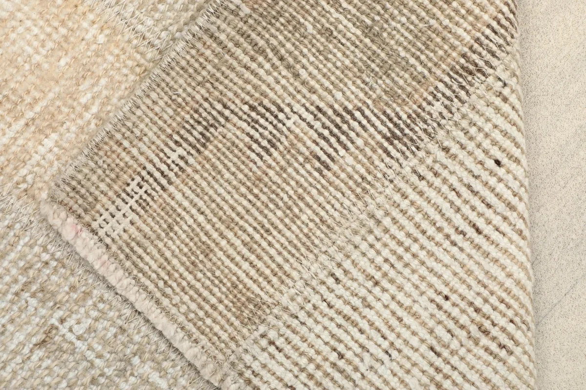 View of the back of the rug, revealing the tightly woven cotton foundation and knotting.