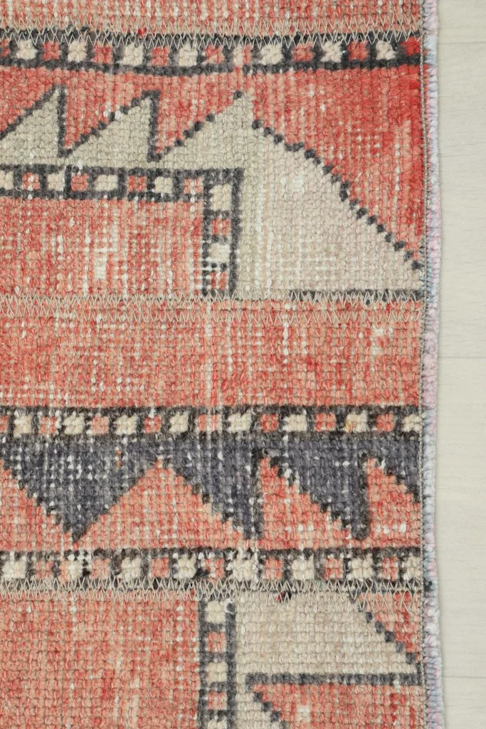Close-up view of the rug's side edge, showcasing the geometric border and the tightly finished edge.