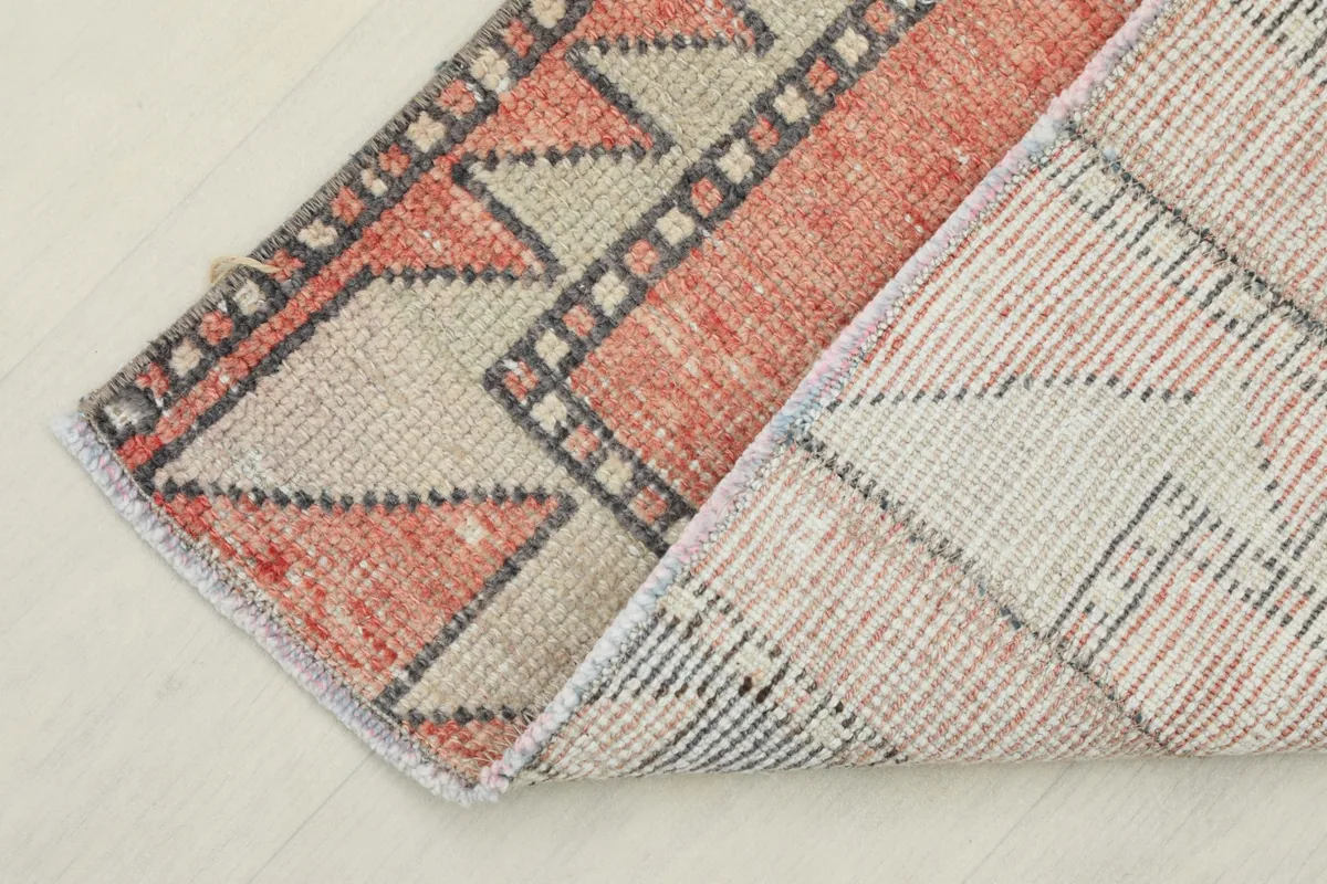 Corner of the rug folded to show the cotton foundation and the reverse side of the hand-knotting.