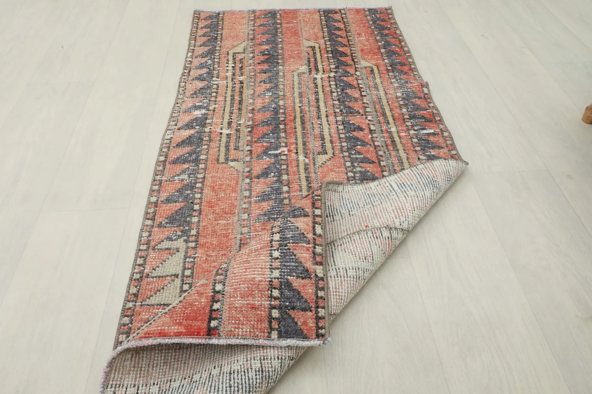 Rug partially folded, displaying the full design from an angle and the texture of the back.