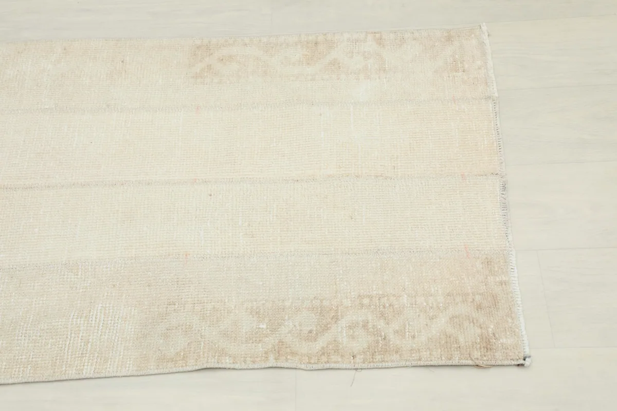 Close-up detail of the subtle beige geometric pattern and texture on one end of the rug