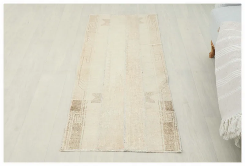 Full overhead view of the cream and beige vintage Anatolian area rug on a light floor.