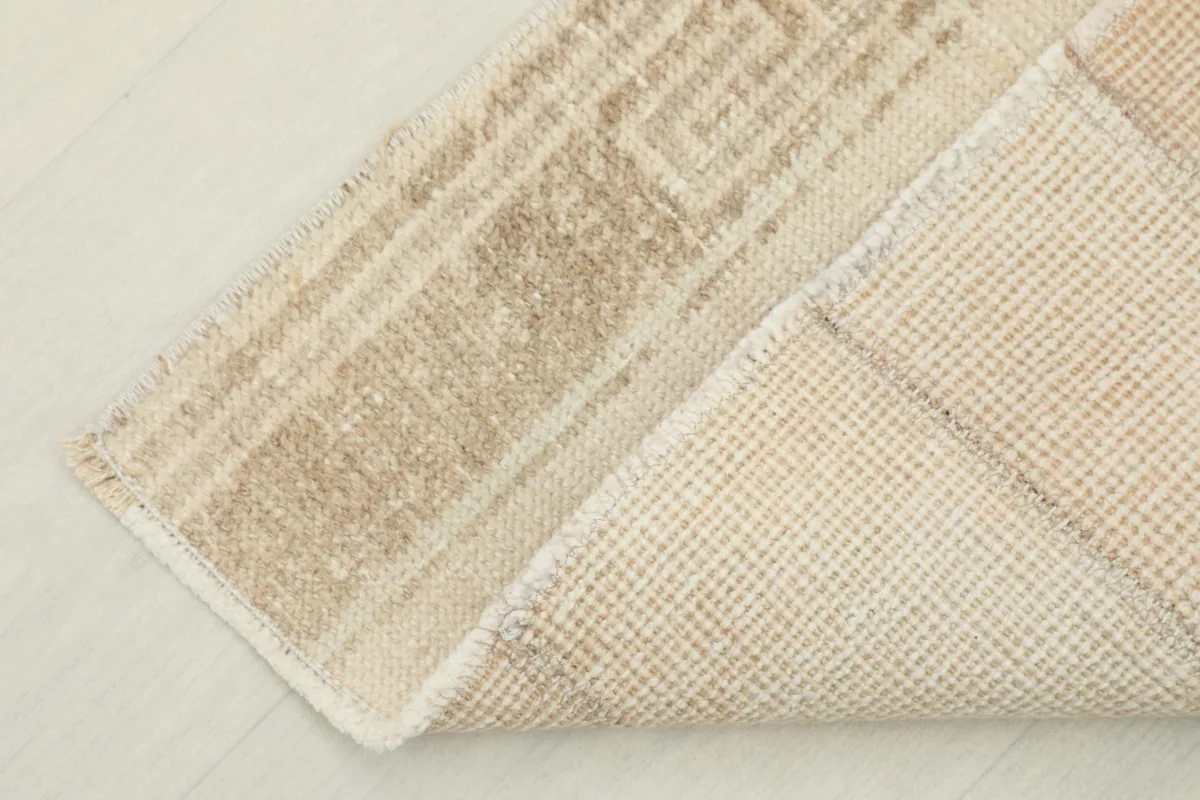 Corner of the rug folded to display both the wool pile surface and the cotton foundation.