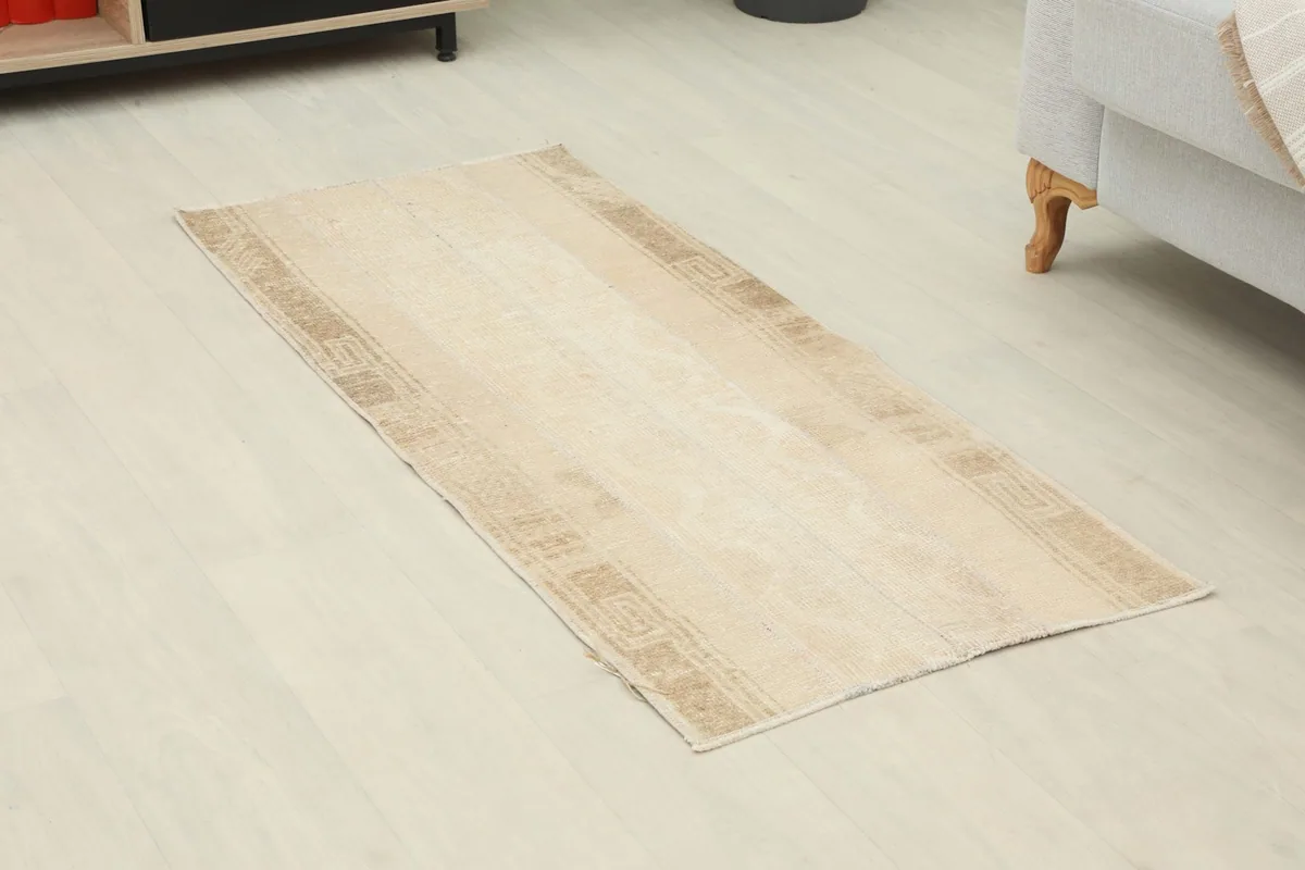 Angled view of the ivory and tan geometric runner rug, showing its placement on a light floor.