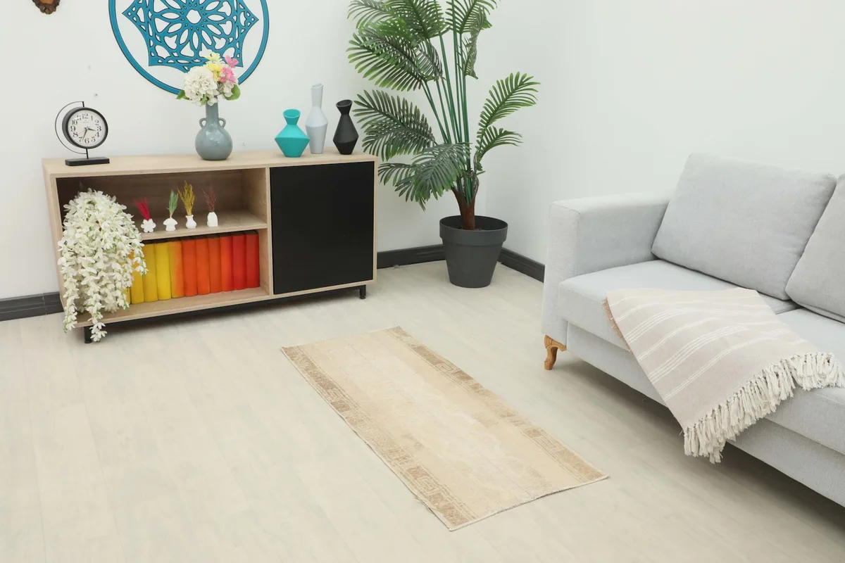 Vintage Anatolian runner rug placed in a modern living space with a gray sofa and wooden cabinet.