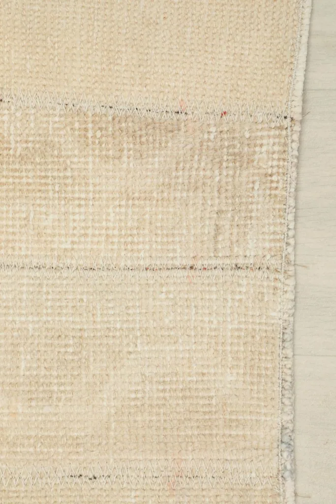 View of the back of the rug, exposing the tightly woven cotton foundation and knot structure.
