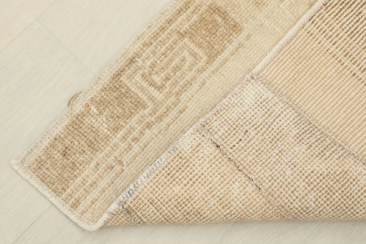 Corner of the rug folded back, displaying the reverse side and the hand-knotted detailing.