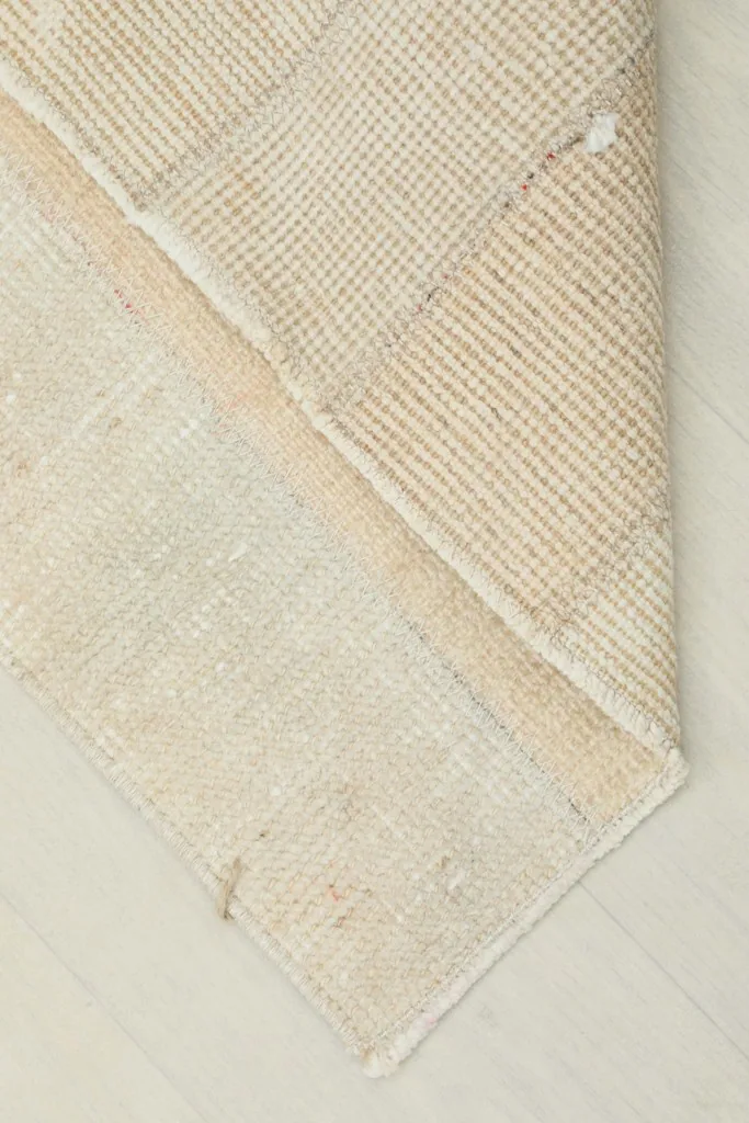View of the back of the rug, revealing the tightly woven cotton foundation