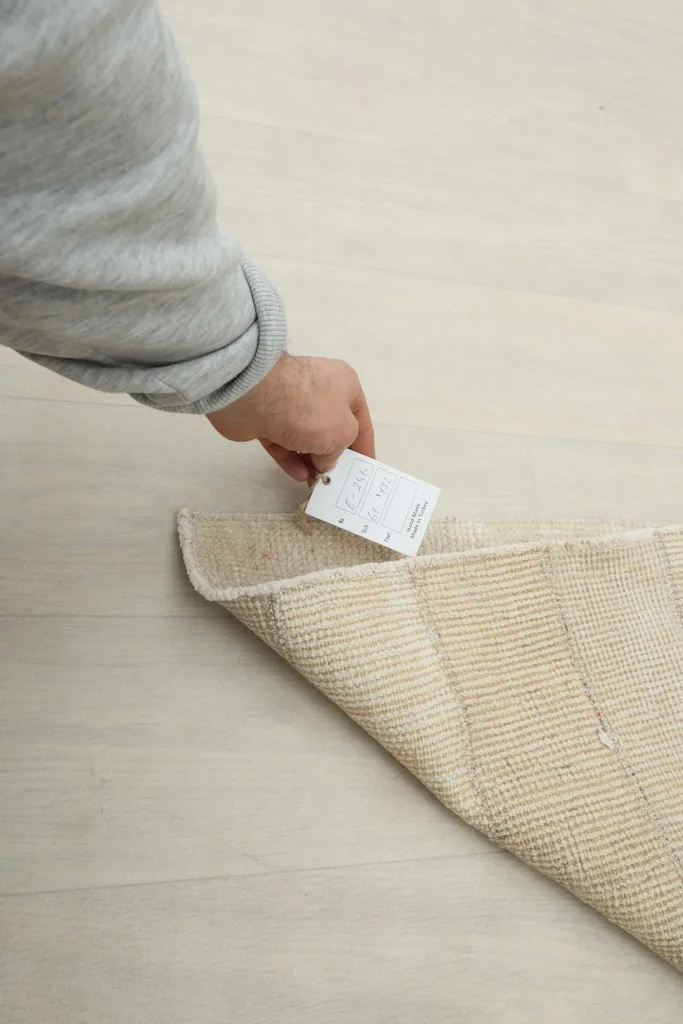 Hand holding a tag on the underside of the vintage Anatolian rug, showing its authenticity