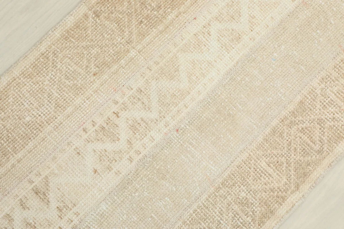 Angled close-up showing the subtle variations in the ivory and beige wool pile and patterns.