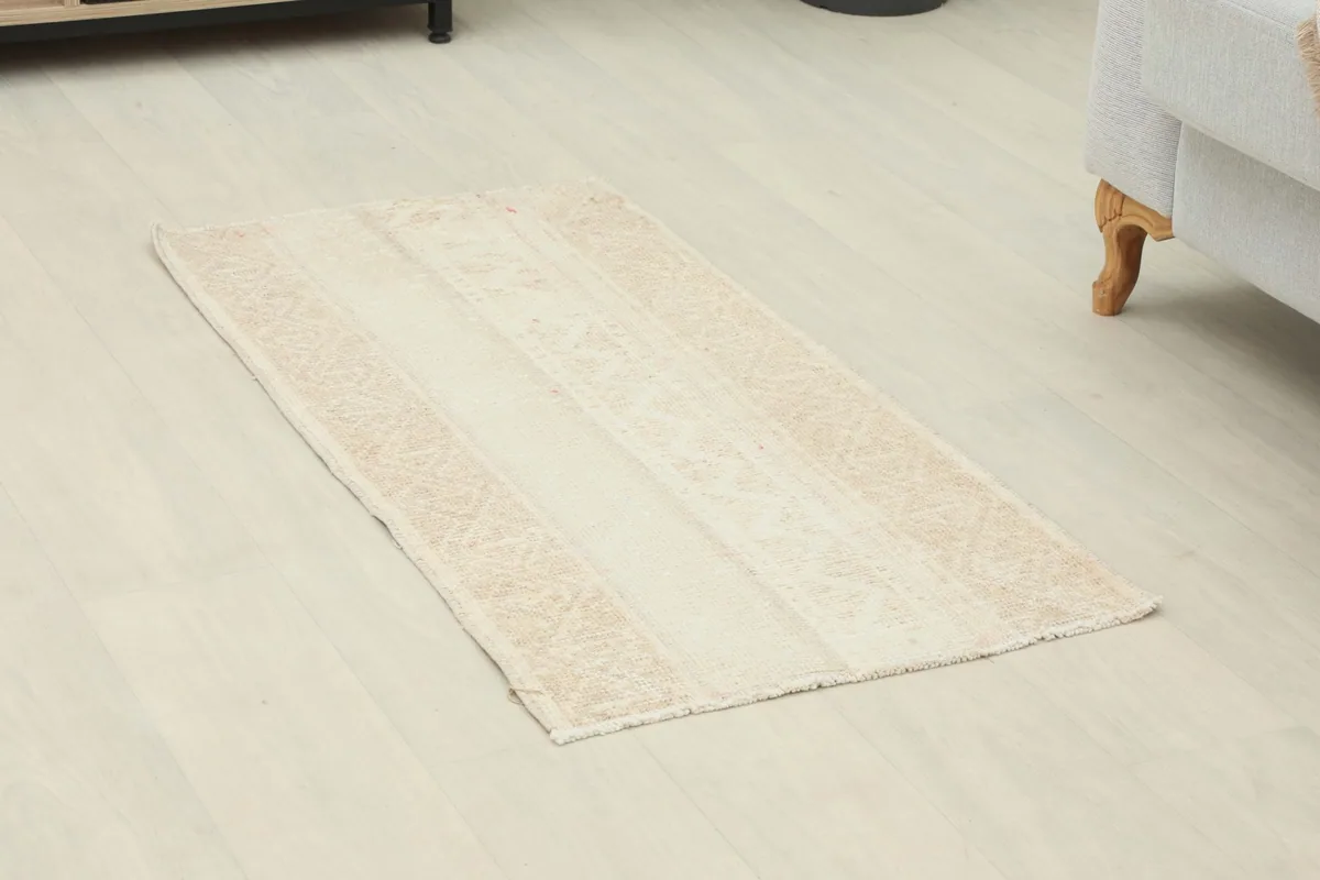Overhead view of the mini ivory and beige rug placed on a light wood floor.
