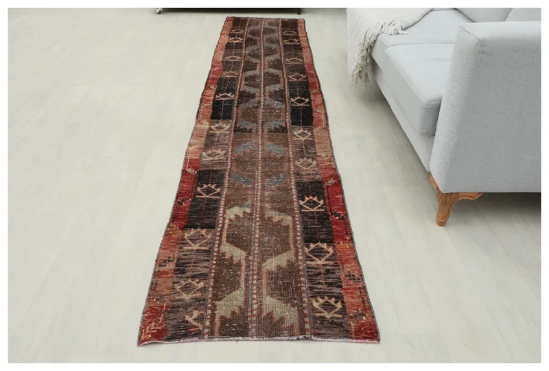 Full top view of the 2'2" x 11'4" vintage Anatolian runner with brown, rust, black, and gray geometric patterns on a