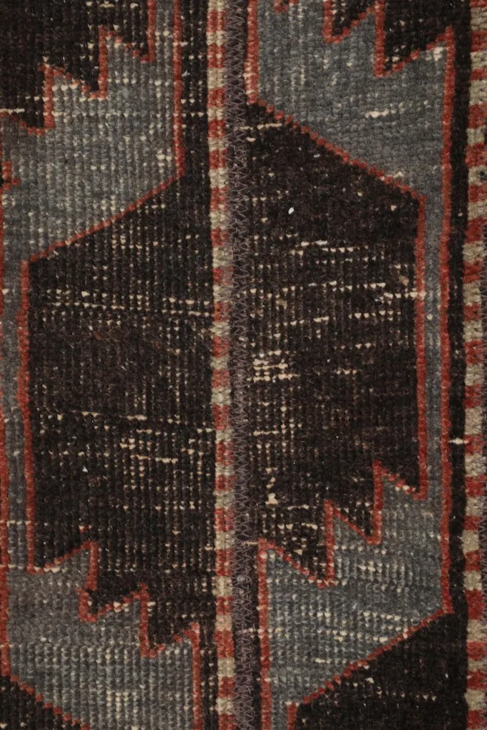 Extreme close-up of the geometric pattern and low pile, revealing individual knots and color blending.