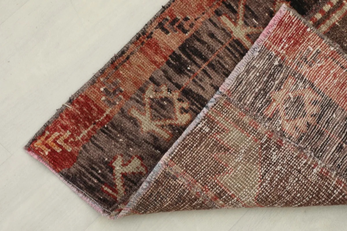 Folded corner of the runner rug, showing the reverse side and the cotton foundation beneath the wool pile.