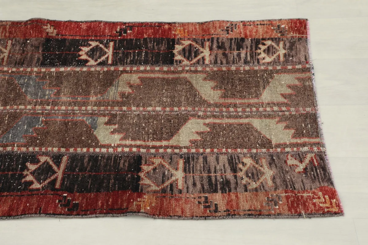 Overhead close-up showing the geometric and tribal motifs in brown, rust, black, and gray across the runner's width.