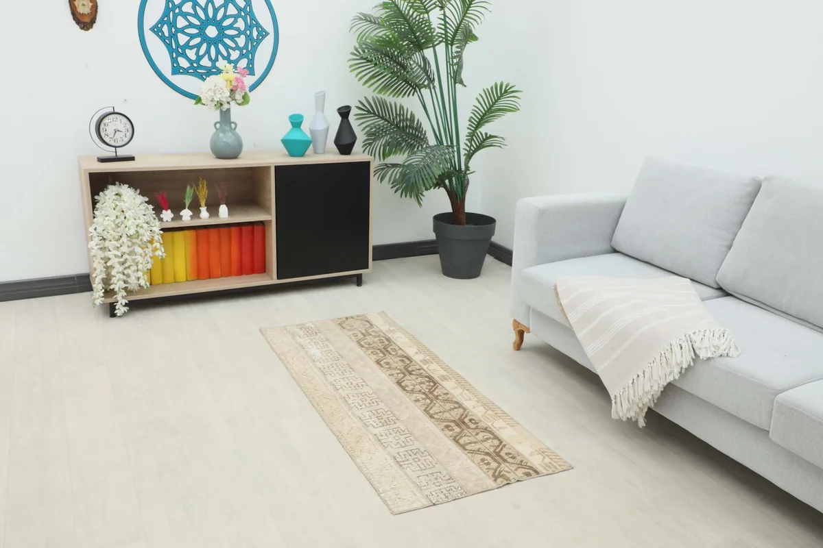 Vintage tan and brown area rug placed in a living room setting next to a sofa and side table.