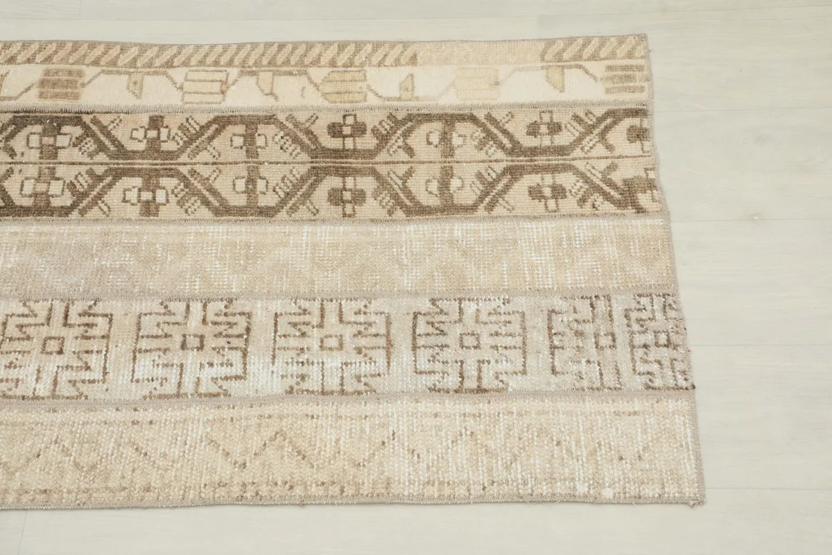 Close-up detail of the geometric patterns and color variations within the tan and brown rug.