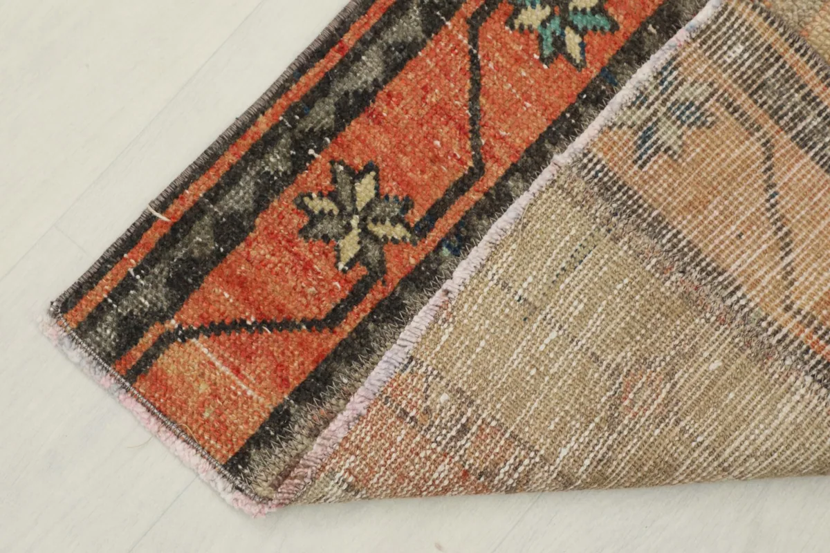 Corner of the rug folded to reveal the hand-knotted wool pile and cotton foundation from the back.