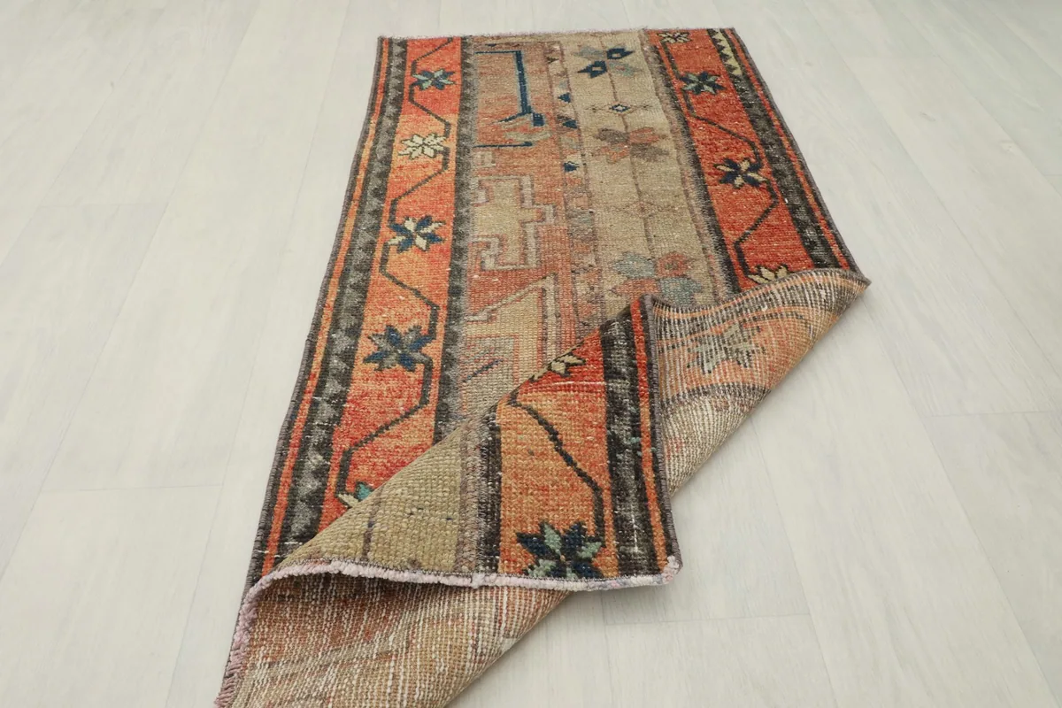 Vintage rug partially folded, displaying its flexibility and the reverse side of the weave.
