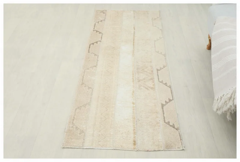 Full overhead view of the 2x6 cream and beige vintage Anatolian runner rug on a white floor.
