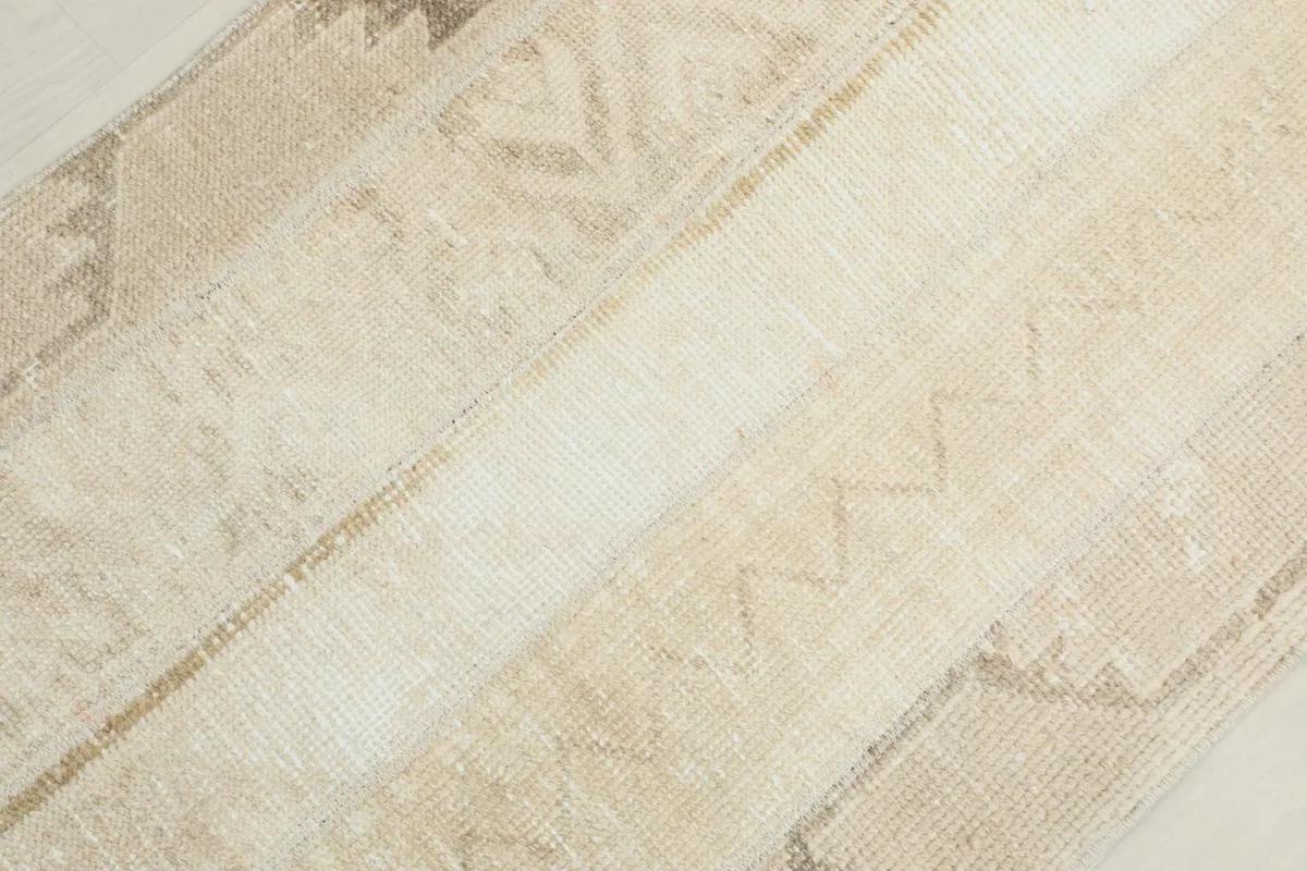 Diagonal detail shot of the rug's vintage wool pile and the subtle zig-zag motifs within the cream field.