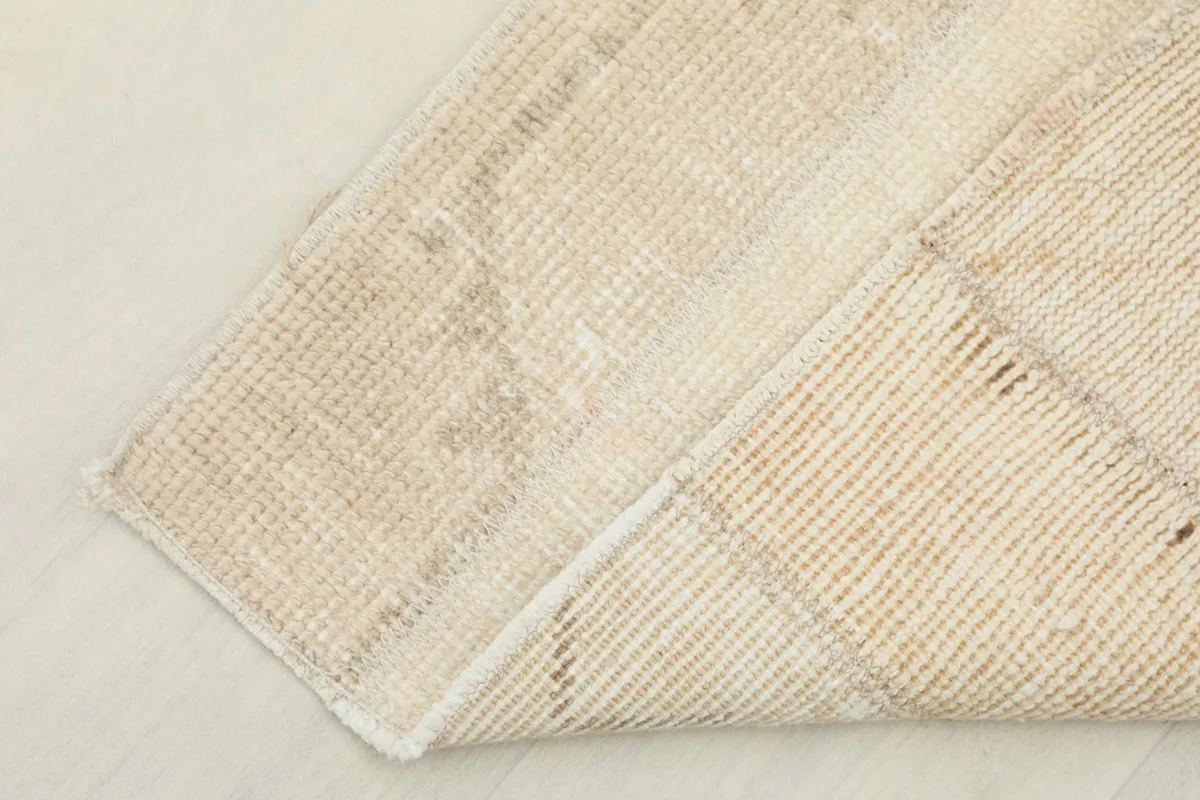 Corner of the rug folded to show the thickness and the backside construction, with visible cotton foundation.