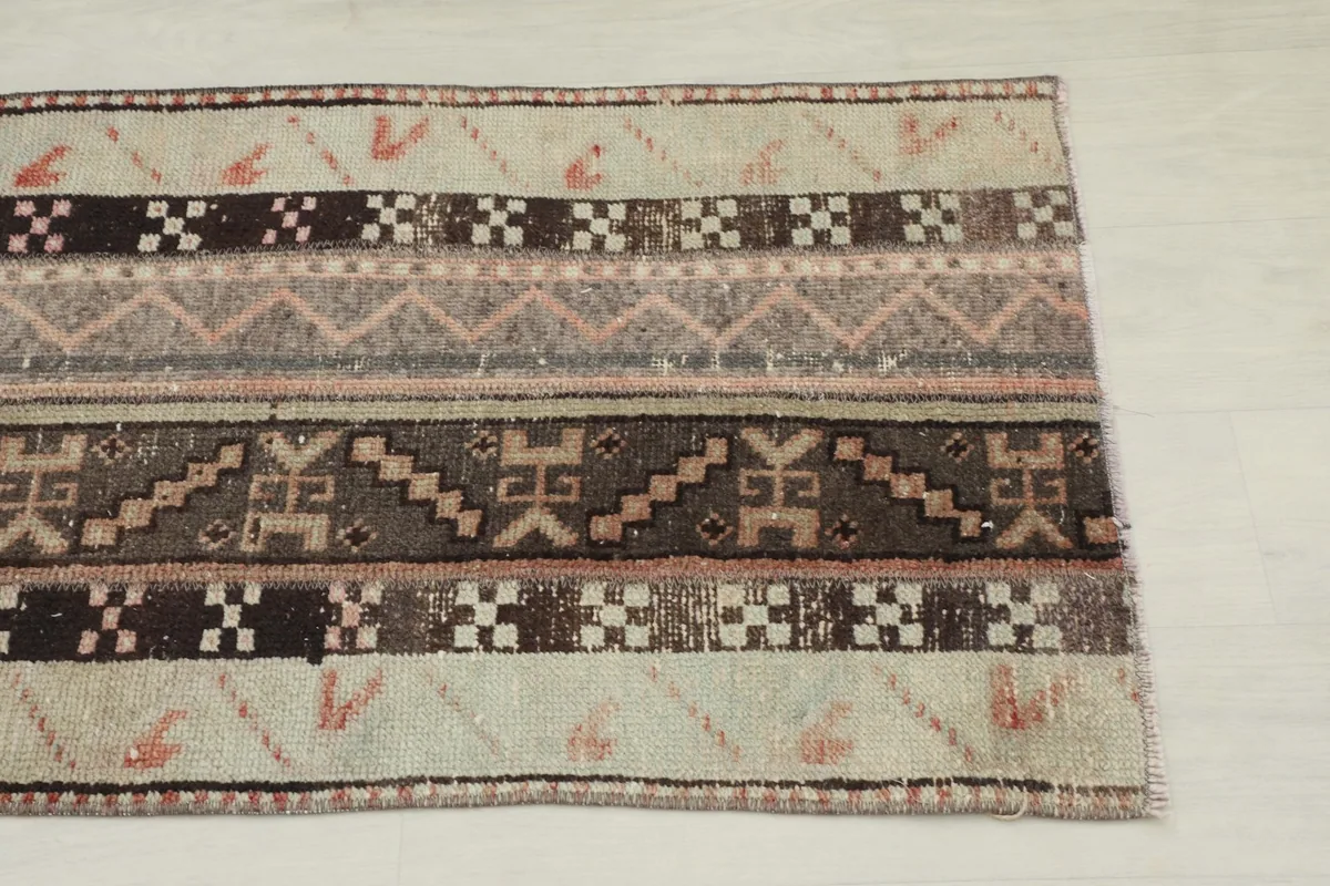 Close-up of one end of the runner rug, highlighting beige, brown, and rose geometric motifs