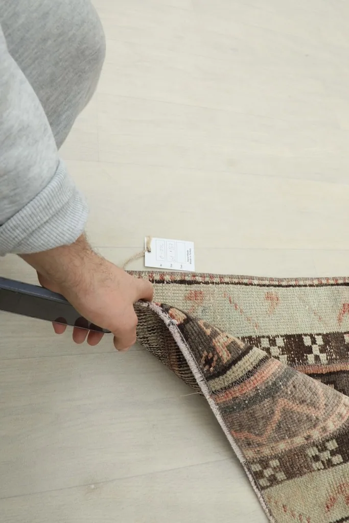 Hand holding the rug to demonstrate its quality and construction near the edge