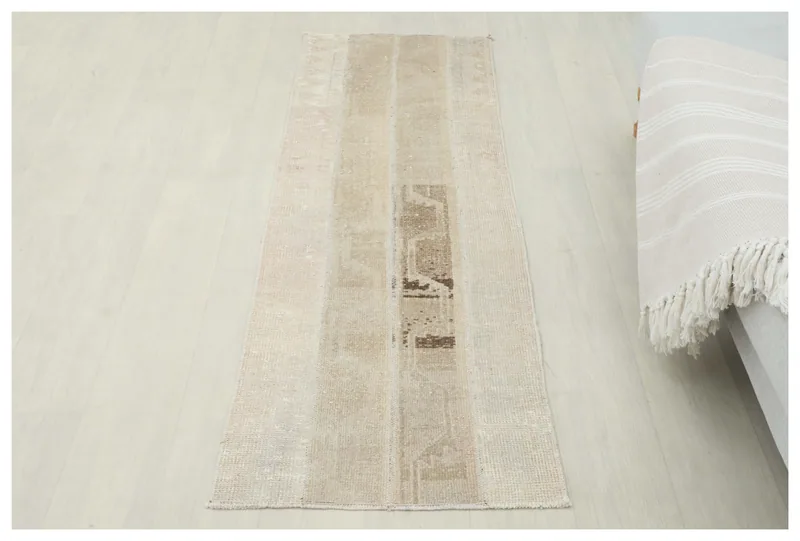 Full overhead view of the beige and tan patchwork runner rug on a light floor