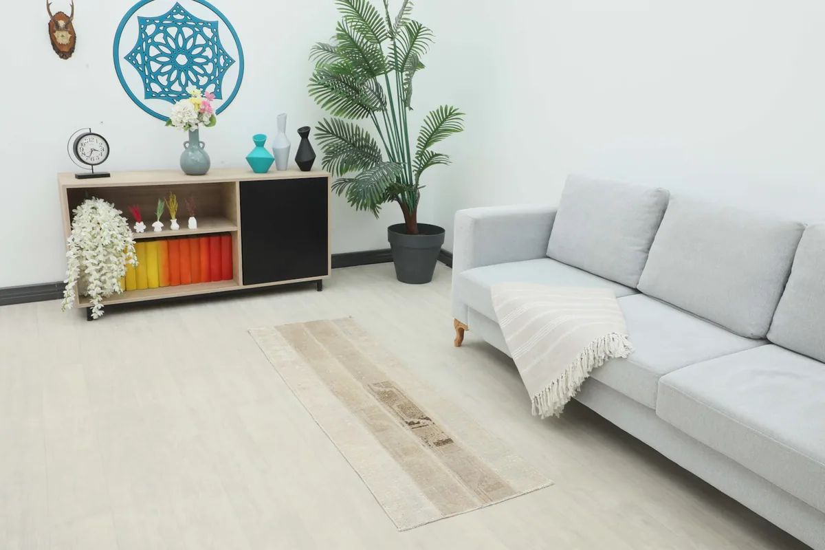 Beige patchwork runner rug placed in a modern living room setting with a sofa and console