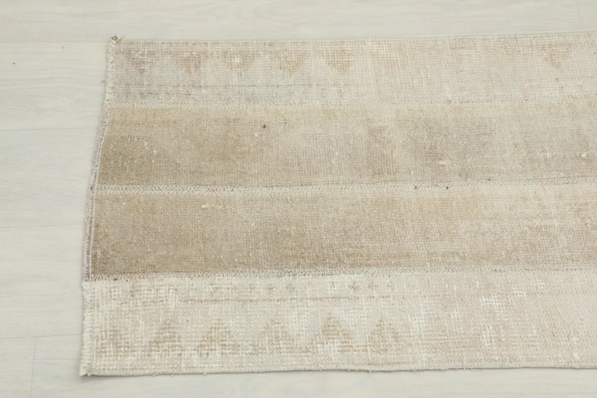 Detail view of the other end of the beige runner rug, showing the subtle geometric patterns