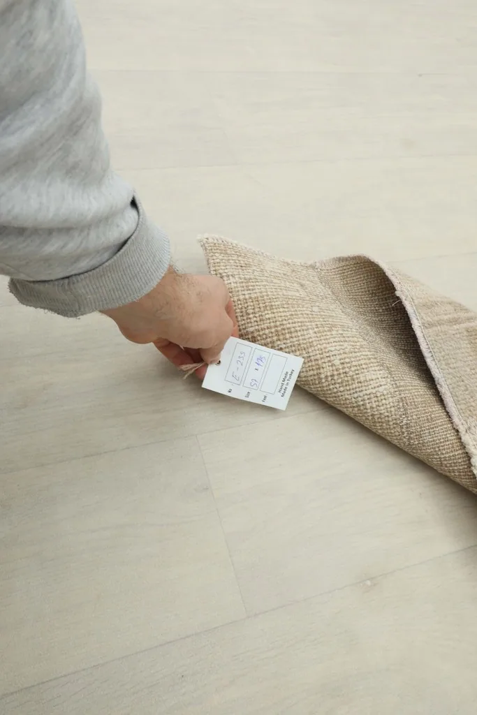 Hand holding the product tag near the folded edge of the hand-knotted vintage runner rug