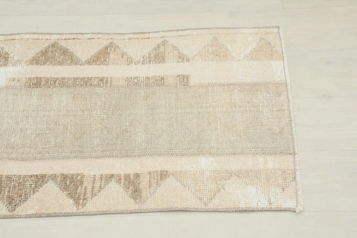 Close-up of one end of the runner rug, highlighting the beige and tan geometric border design.