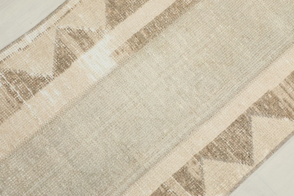 Diagonal close-up of the rug's surface, revealing the texture of the low wool pile and color blend.
