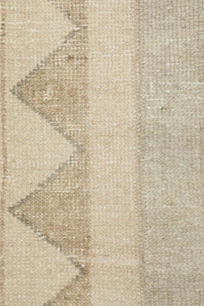 Detailed view of the rug's border, showcasing the hand-knotted wool and tribal triangular motifs.