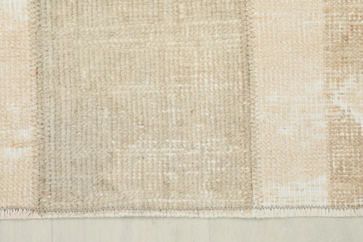 Close-up of the rug's low pile, showing the tight weave and subtle variations in beige and tan wool.