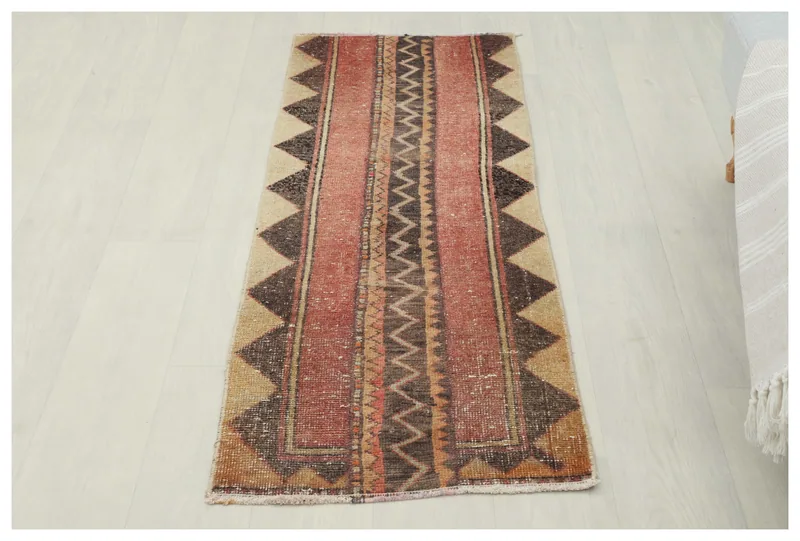 Full top view of the vintage red and tan geometric runner rug on a white background.